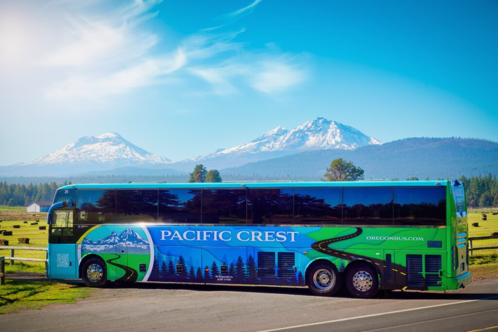 Pacific Crest Bus Lines Charter bus parked next to a field with three sister mountain in the background