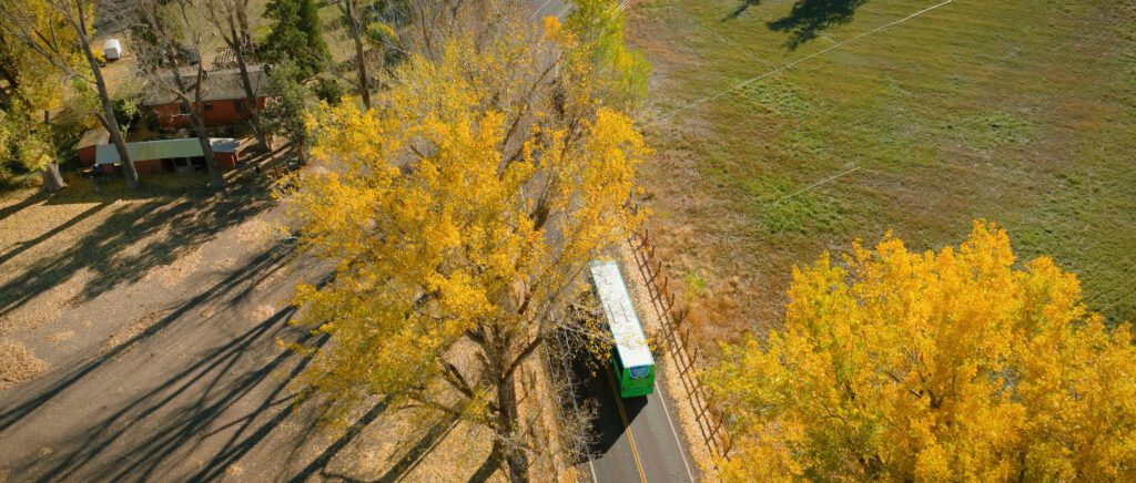 Aerial view of a PCBL traveling down the rod going under fall colored trees
